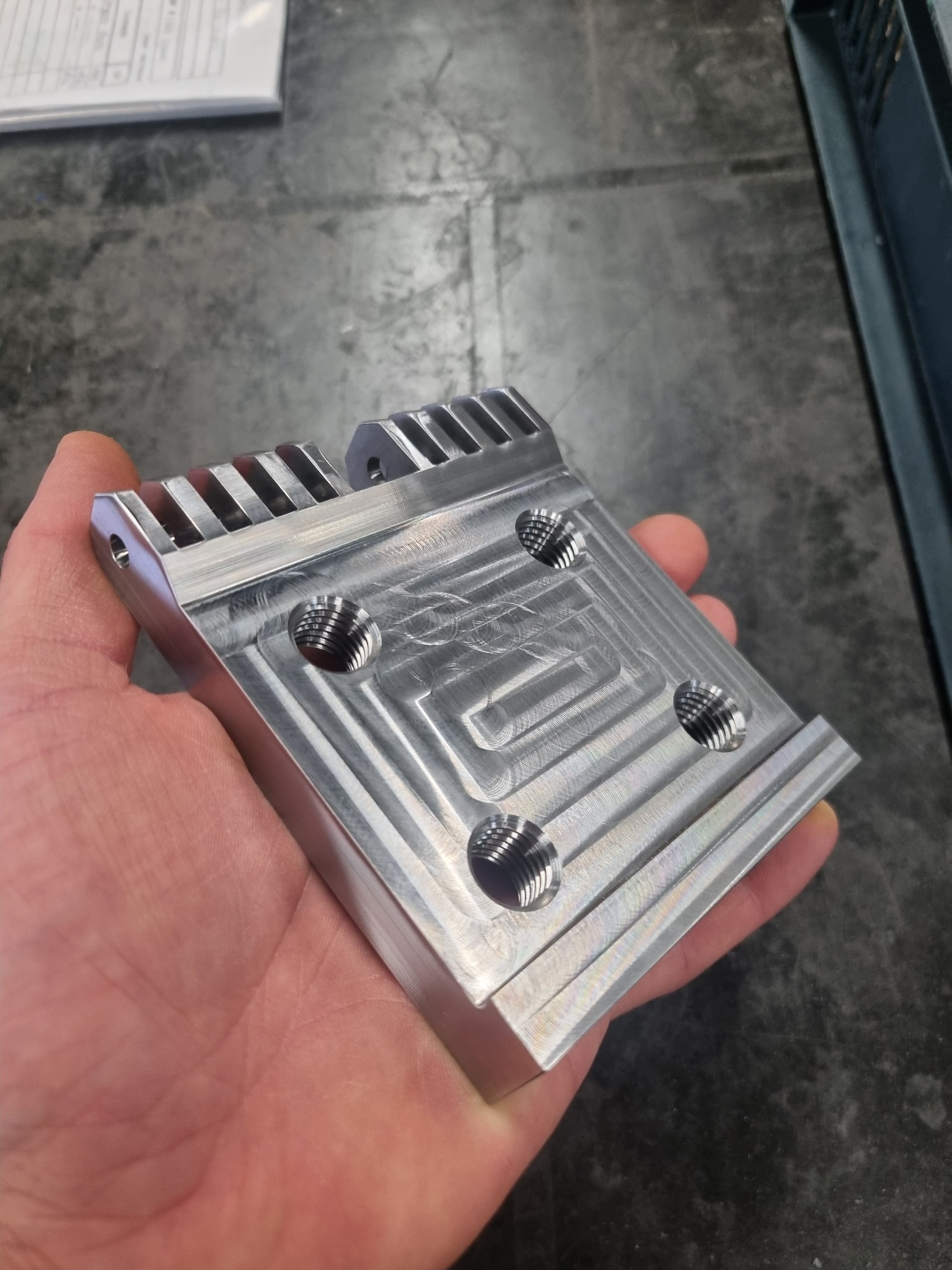 Precision machined component shown in hand for scale